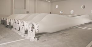 9 white wind turbine blades on a factory floor.