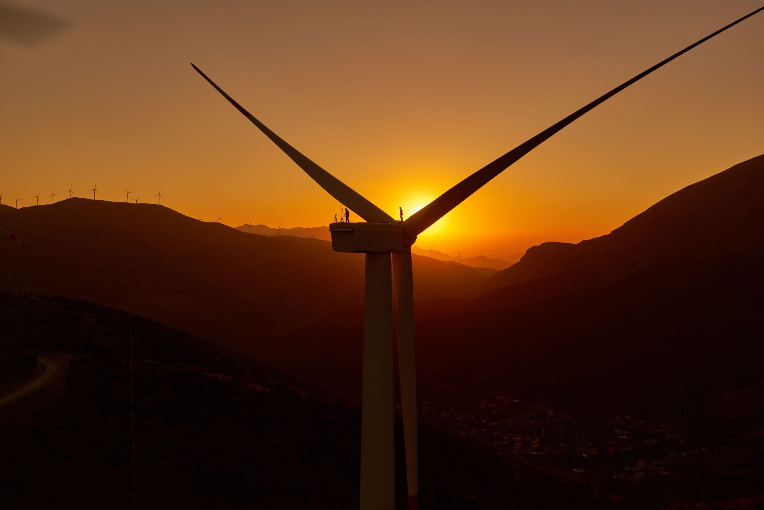 Close up of a wind turbine with a sunset behind.